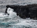 Mesmerizing view of sea waves splashing against a large piece of rock on a gloomy day Royalty Free Stock Photo