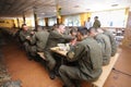 At a mess hall: soldiers sitting at set-out tables and eating
