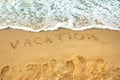 Message for the beach written with the word vacation in smooth sand with incoming wave Royalty Free Stock Photo