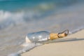 Message in bottle on beach with white sand, in tropical sea. Sunny blue sea horizon Royalty Free Stock Photo