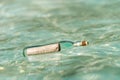 Message in a bottle washed ashore on tropical beach.