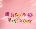 Message HAPPY BIRTHDAY made of colorful letters in a frame made of flowers on pink background. Birthday party concept Royalty Free Stock Photo