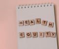 Message health equity with wooden letters on notebook in pink Royalty Free Stock Photo