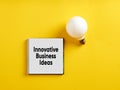 The message innovative business ideas on notepad with a light bulb. Innovation and creative ideas in business Royalty Free Stock Photo