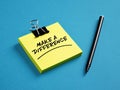 The message make a difference on yellow sticky note paper with a black pen on blue background Royalty Free Stock Photo