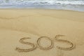 Message SOS drawn on sand near sea Royalty Free Stock Photo