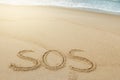 Message SOS drawn on sand near sea Royalty Free Stock Photo