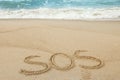 Message SOS drawn on sand near sea Royalty Free Stock Photo