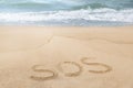 Message SOS drawn on sand near sea Royalty Free Stock Photo