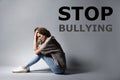 Message STOP BULLYING and sad woman sitting