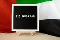 Message text EID MUBARAK - happy holidays waving UAE flag on background concept. Greeting card advertisement Royalty Free Stock Photo