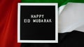 Message text HAPPY EID MUBARAK - happy holidays waving UAE flag on background concept. Greeting card advertisement Royalty Free Stock Photo