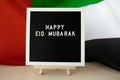 Message text HAPPY EID MUBARAK - happy holidays waving UAE flag on background concept. Greeting card advertisement Royalty Free Stock Photo