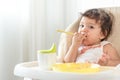 Messy baby girl eating cake. Lovely infant girl holding a spoon, enjoying eating cake