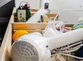 Messy bathroom drawer with hairdryer and small container boxes