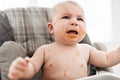 Messy and dirty baby is eating snack and crying. Royalty Free Stock Photo