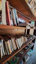 messy and dusty books piled up on a wooden bookshelf