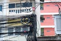 Messy electrical cables in thailand - many lines of cables chaotic set of interwoven, optical fiber technology open air outdoors Royalty Free Stock Photo