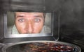 Messy and funny dummy man in the kitchen looking through microwave or oven pizza burning overcooked making a mess of home cook in Royalty Free Stock Photo