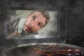 Messy and funny dummy man in the kitchen looking through microwave or oven pizza burning overcooked making a mess of home cook in Royalty Free Stock Photo