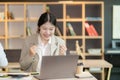 Messy and happy Asian beautiful woman celebrating success with arms raised in front of laptop. Royalty Free Stock Photo