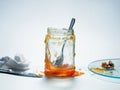 Messy jar of homemade apricot preserves with spoon and knife beside plate with biscuit crumbs Royalty Free Stock Photo