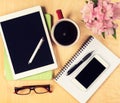 Messy office table with digital tablet, smartphone, reading glasses, notepad and cup of coffee. View from above