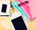 Messy office table with digital tablet, smartphone, reading glasses, notepad and filling folders. View from above