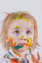 Messy painted child. Paint on the face and clothes. The baby looks up innocently. Children`s pranks