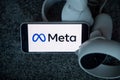 META company logo on smartphone next to Oculus joy cons, touch controllers.