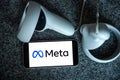 META company logo on smartphone next to Oculus joy cons, touch controllers.