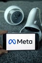 META company logo on smartphone next to Oculus joy cons, touch controllers.