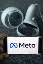 META company logo on smartphone next to Oculus joy cons, touch controllers.