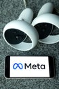 META company logo on smartphone next to Oculus joy cons, touch controllers.