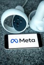 META company logo on smartphone next to Oculus joy cons, touch controllers.