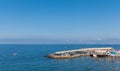 Small water pier full of cars next to small beach with a lot of people swimming in water