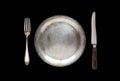 Metal antique plate, knife and fork isolated on a black background