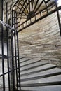 Metal antique spiral staircase with handrails in a stone tower.