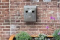 Metal ashtray on a brick stone wall with some plants and flowers