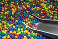 Metal baby slide going down to the pool with many colored balls in the kids playing room