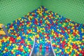 Metal baby slide going down to the pool with many colored balls in the kids playing room Royalty Free Stock Photo