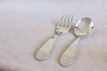 Metal reusable baby spoon and fork on table cloth with copy space. Tableware for kid. Refuse using plastic dishes for