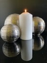 3 metal balls reflected in a glass table with candle