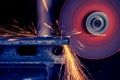 Metal bar being cut with electric grinder with spark flying, selective focus