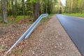 Metal barrier at the asphalt road in the forest. A dangerous place protected by a railing Royalty Free Stock Photo