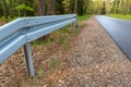 Metal barrier at the asphalt road in the forest. A dangerous place protected by a railing Royalty Free Stock Photo