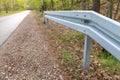 Metal barrier at the asphalt road in the forest. A dangerous place protected by a railing Royalty Free Stock Photo