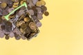 A metal basket filled with golden-colored coins against a scattering of yellow coins. Royalty Free Stock Photo