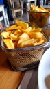 Metal basket of fried potatoes on a restaurant table. The Belgians and the French contended for their authorship Royalty Free Stock Photo