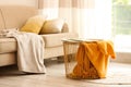 Metal basket with yellow blanket in room, space for text. Idea for interior design